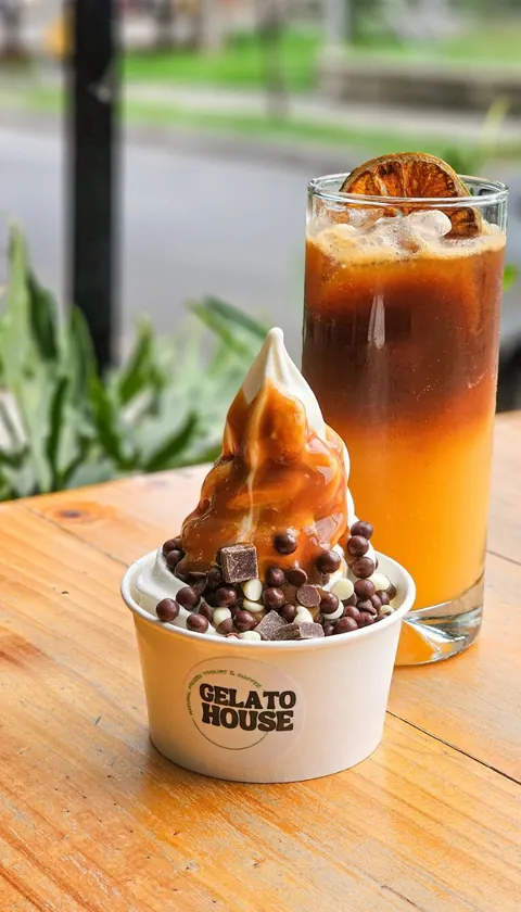 Helado de yogurt con toppings de chocolate junto a una bebida fría